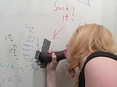 Blonde amateur licks and sucks a big black dong through a wall