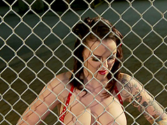 Busty pinup girl Emily Parker sucks cock through a fence