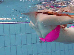 Petite redhead chick in pink bikini getting naked in the pool