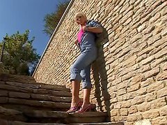 Pretty Dorina fingers her wet pussy on the stairs in the street